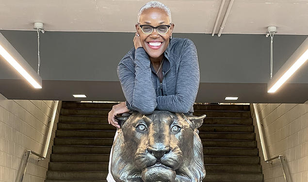 Deborah Saint Phard leans forward over a statue of a tiger.