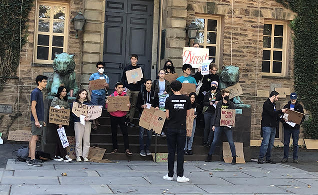 Students with Divest Princeton hold signs in front of Nassau Hall, made of cardboard and showing their support for Princeton divesting from fossil fuels.
