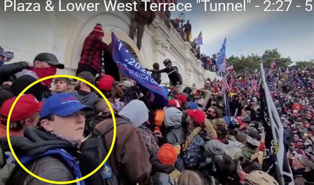 A yellow circle has been drawn about a boy in the foreground, wearing a blue baseball cap. In the background a crowd climbs over the wall around the Capitol.