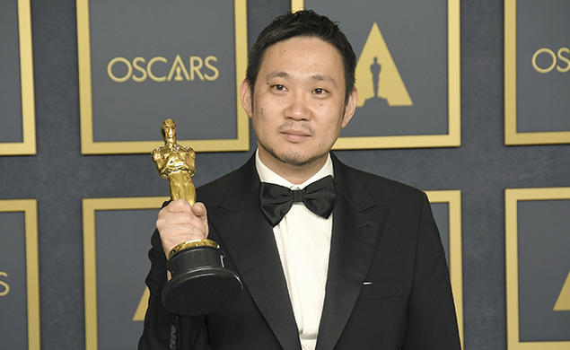 Director Ryusuke Hamaguchi holds an Oscar statue.