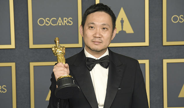 Director Ryusuke Hamaguchi holds an Oscar statue.