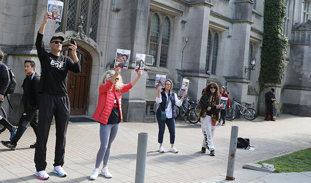 Howard Levy ’85, left, holds up photos of Israeli hostages at the pro-Palestinian student encampment in McCosh Courtyard on April 25.