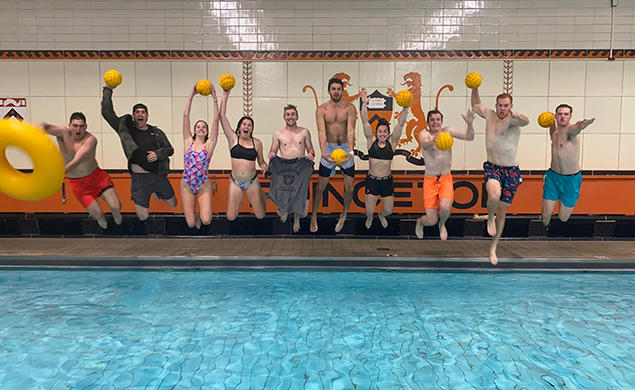 Holding yellow water polo balls, Princeton’s intramural water polo team jumps into the pool.