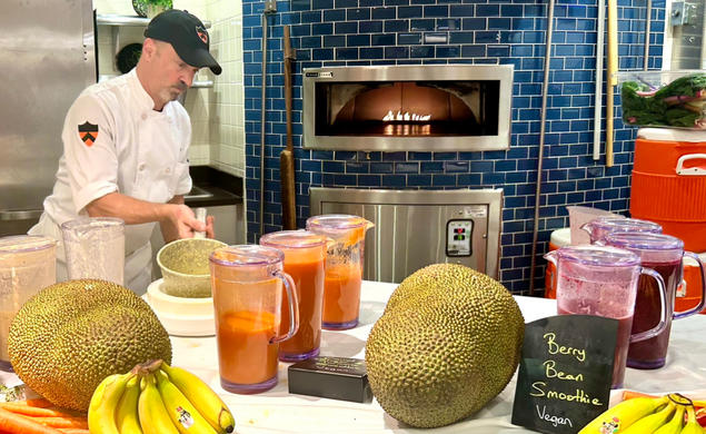 Dining staff prepare vegan berry bean smoothies on a table with bananas and jackfruit.