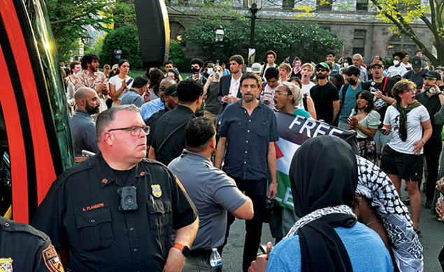 Max Weiss, a professor of history, stands at the April 29 Clio Hall occupation between protesters and Public Safety officers, who detained a student and a postdoc in a University bus.