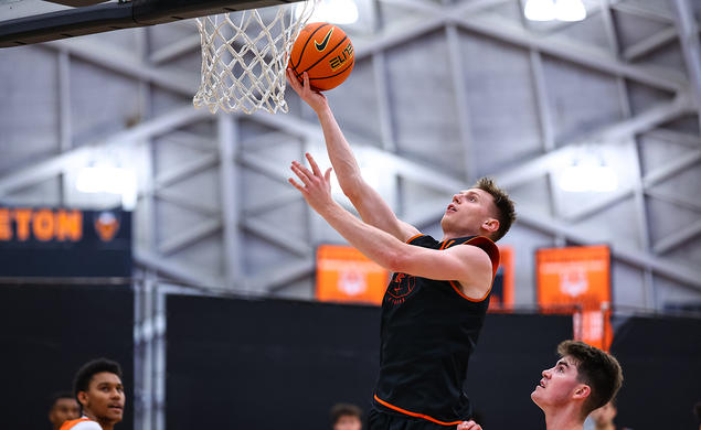 A man lifts a ball nearly to the rim of the basket.