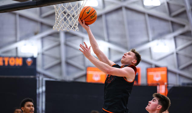 A man lifts a ball nearly to the rim of the basket.