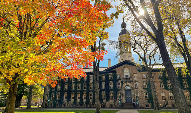 Nassau Hall in the fall, with trees turning yellow, red and orange.