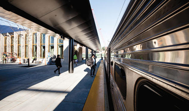 Passengers board the Dinky at the new transit plaza; the rail station is at left.