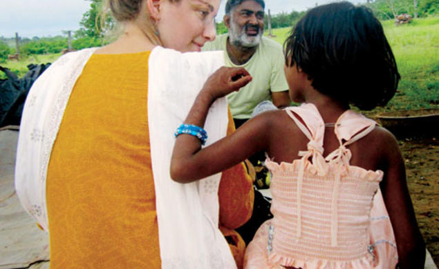 Shaina Watrous ’14, director of a documentary about Ajeet Singh, center, listens to a child in Varanasi, India.
