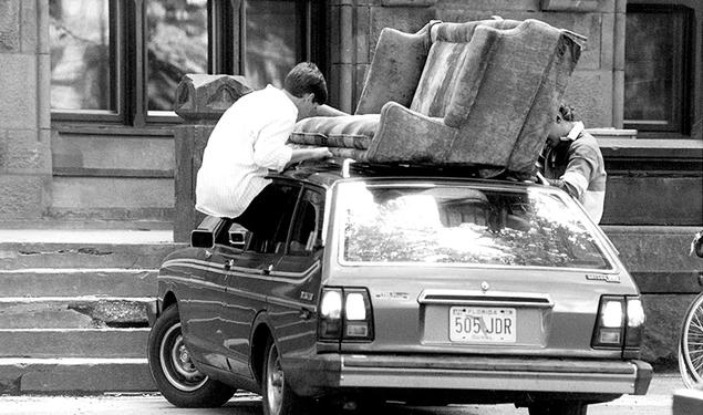 Students removing couch from the roof of a car