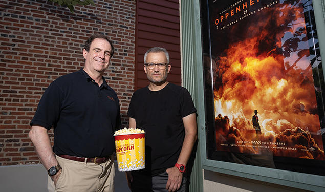 Mark F. Bernstein ’83, left, and Alexander Glaser with popcorn and the Oppenheimer movie poster.