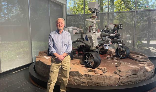 Photo of Chad Edwards ’79 in front of a full-scale model of the Perseverance rover