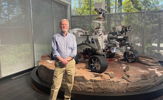 Photo of Chad Edwards ’79 in front of a full-scale model of the Perseverance rover