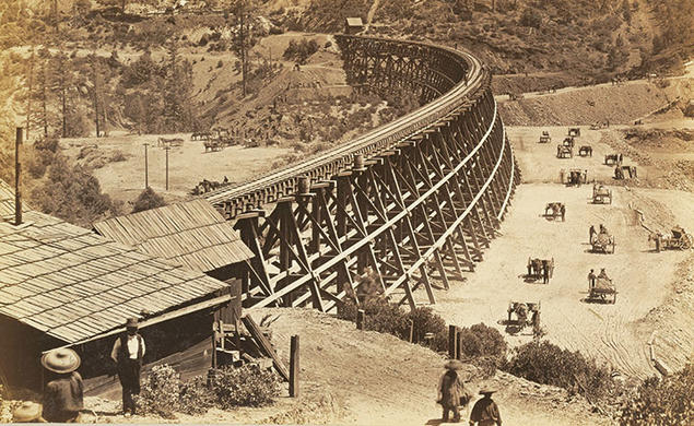 Chinese workers fill in a ravine alongside a large trestle for the Transcontinental Railroad in this photo, taken in 1867.