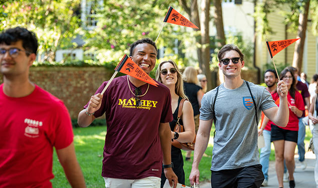 Waving orange pennants, students march in the 2023 Pre-rade.