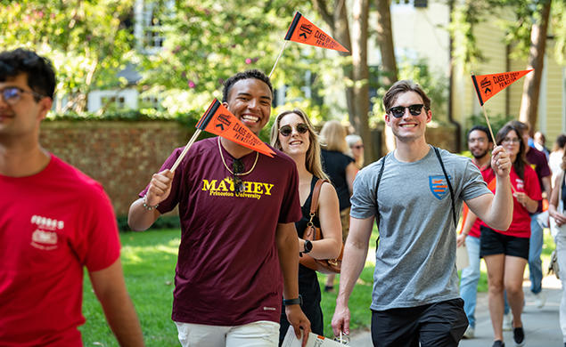 Waving orange pennants, students march in the 2023 Pre-rade.