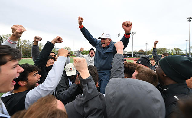 Cheering students hoist Fred Samara onto their shoulders; he holds up two fists to signal victory. 