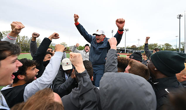 Cheering students hoist Fred Samara onto their shoulders; he holds up two fists to signal victory. 