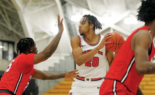This is a photo of Tosan Evbuomwan ’23 playing against Marist in November. He's holding the ball to his left and looking right while another player tries to block him.
