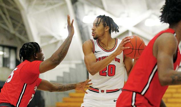 This is a photo of Tosan Evbuomwan ’23 playing against Marist in November. He's holding the ball to his left and looking right while another player tries to block him.