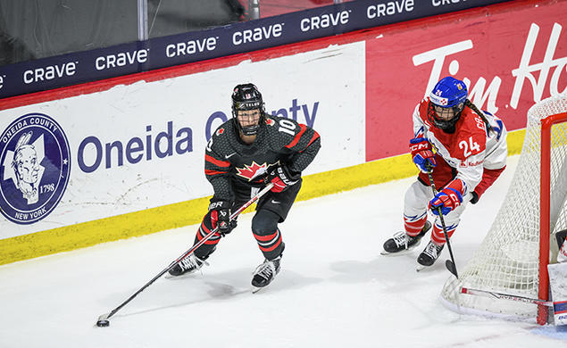 Two hockey players skate around the back of the goal.