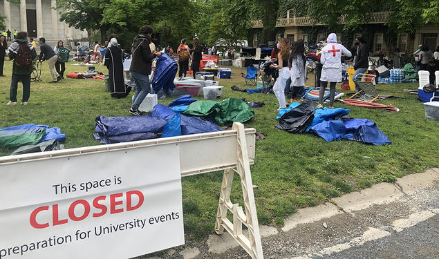 Protesters clean up Cannon Green behind a sign saying the area is now closed in preparation for University events. 