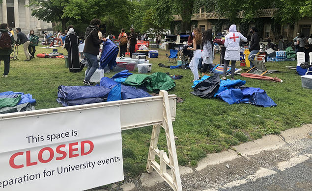 Protesters clean up Cannon Green behind a sign saying the area is now closed in preparation for University events. 