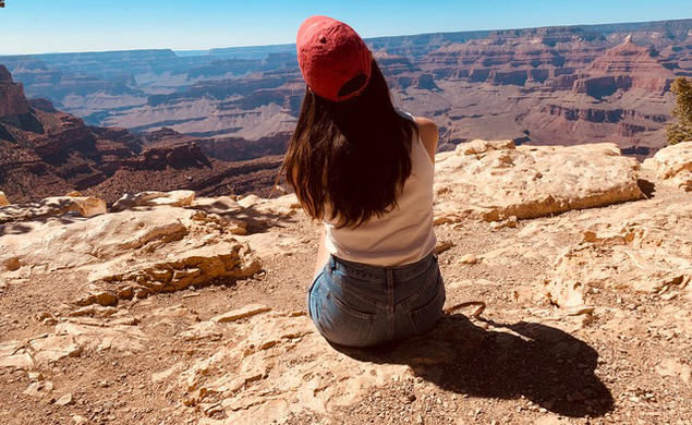 Cassandra James ’23 sits with her back to the camera, looking over a southwest scene.