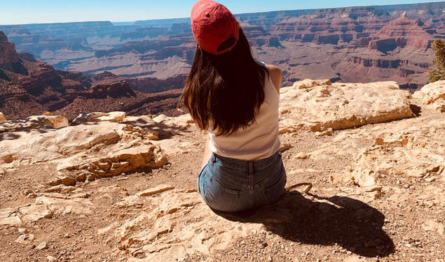 Cassandra James ’23 sits with her back to the camera, looking over a southwest scene.