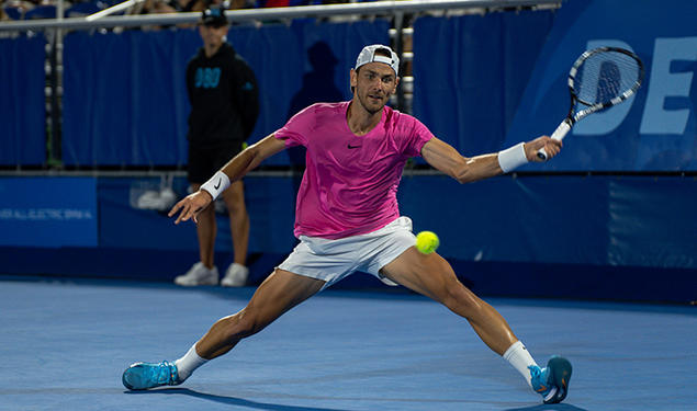 Matija Pecotić ’13 hits a tennis ball with a racket in his left hand