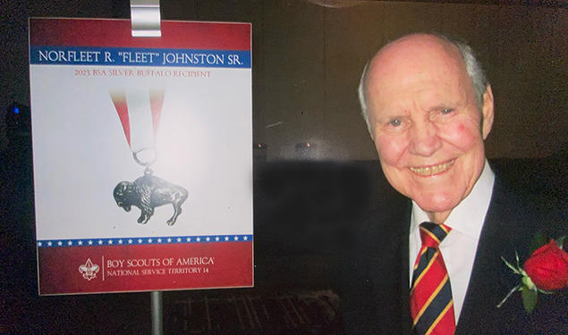 Norfleet Johnson ’56 next to a sign from the Boy Scouts of America about his Silver Buffalo award.