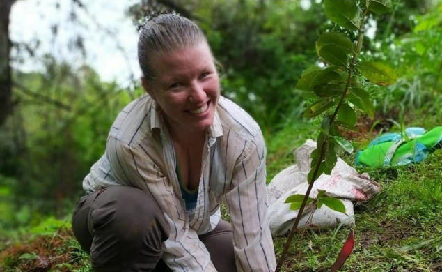 Ruth Metzel smiles as she lowers a plant into the ground.