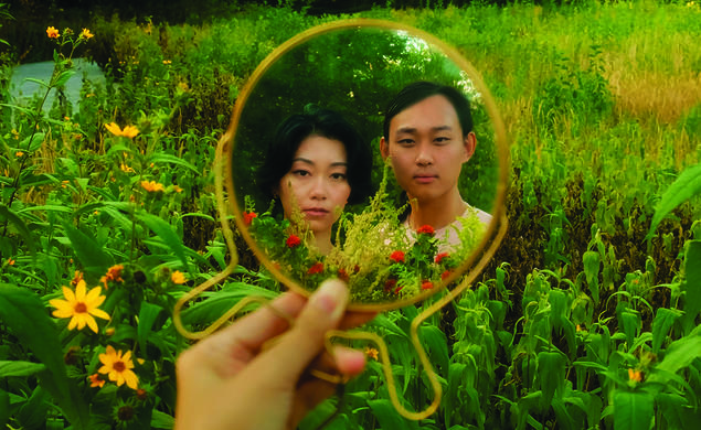 Two people in a field, reflected in a round mirror.