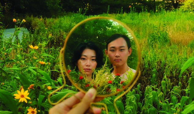 Two people in a field, reflected in a round mirror.