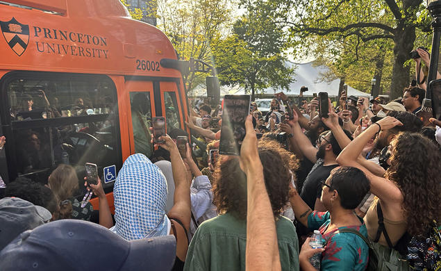 Protesters surrounding a University bus, holding up cell phone cameras