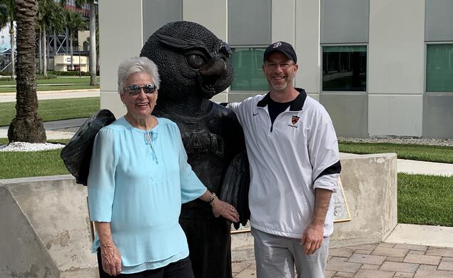 Two people stand with a statue.
