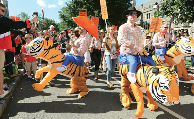 This is a photo from the P-rade in 2017 of the Class of 2002 riding inflatable tigers. One is wearing an orange cowboy hat.
