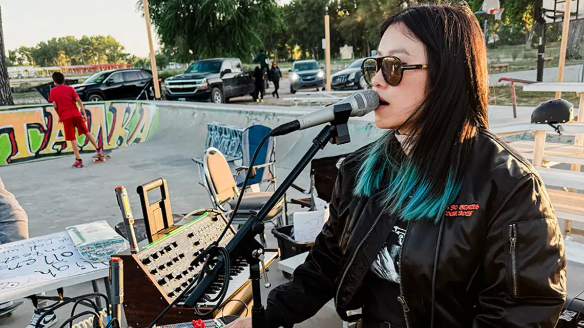 Vocalist Charmaine Lee ’14 Is Taking Her Mind-Bending Music to All 50 States A woman sings into a microphone in a skate park.