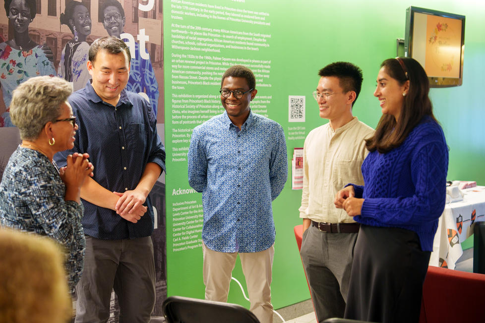 Five people conversing at the opening of an exhibition