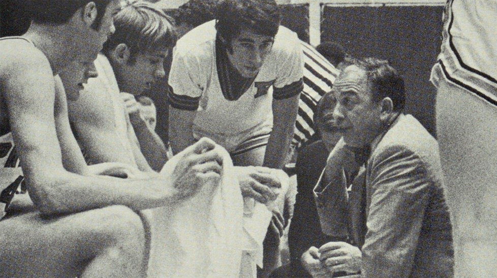 Coach Pete Carril kneels down to speak with his players on the sideline