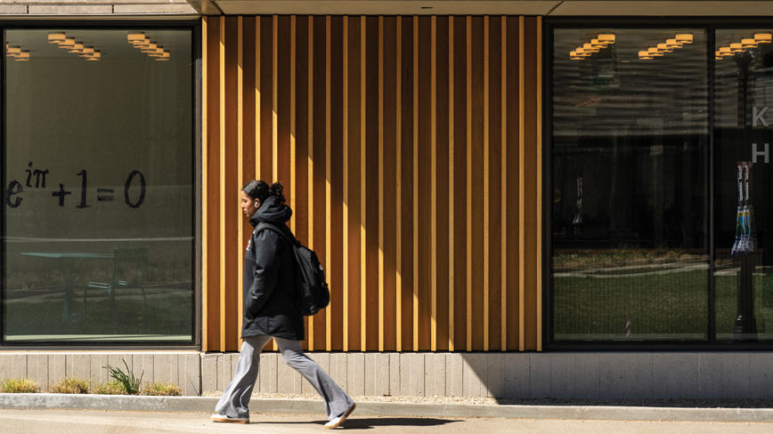 Studetn walking past the Yeh and New College West residential colleges with their modern architecture