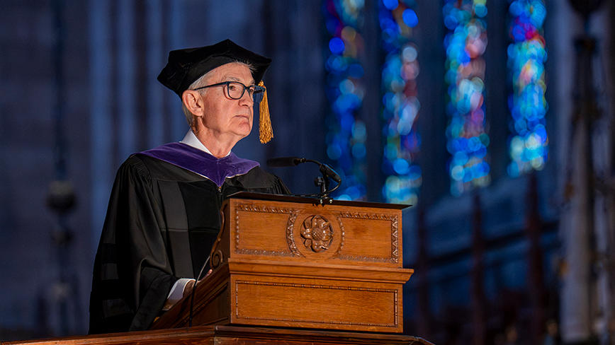 Jerome Powell speaks at a podium in the Princeton Chapel, a stained glass window in the background.