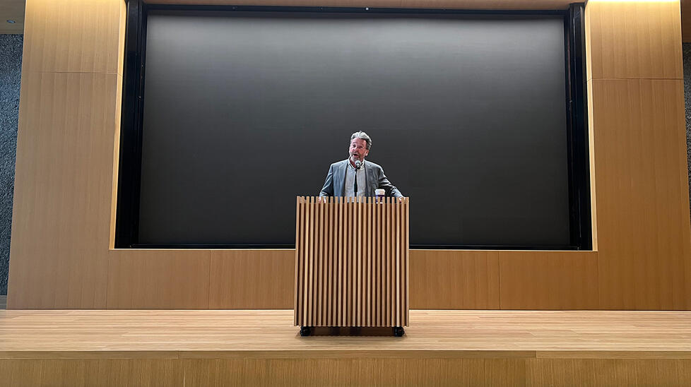ARTMUSEUM_JamesStewart.jpg A man speaks at a wooden podium.