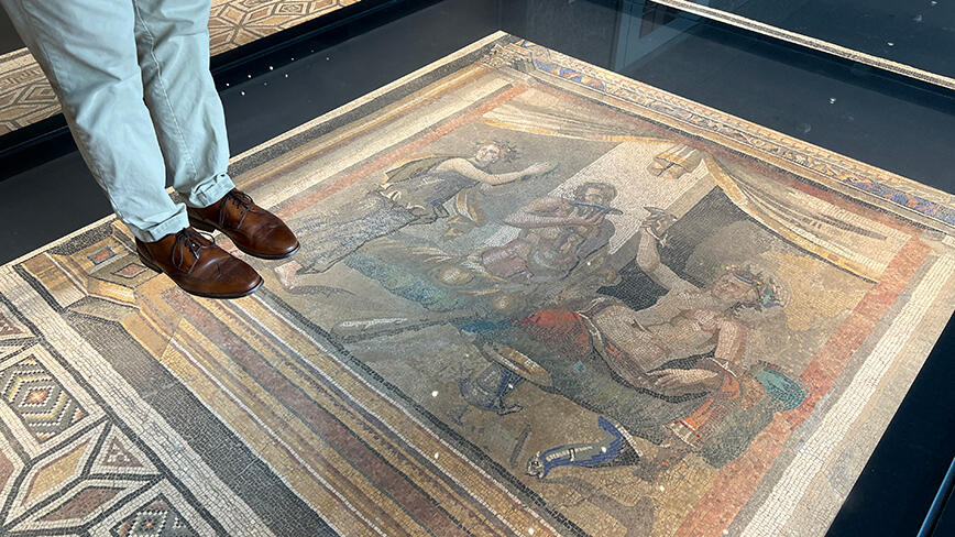 Mark_feet_mosaic.jpg Someone's legs as they stand on the glass over a Roman mosaic installed in the floor.