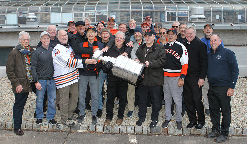 A crowd of about 20 alumni gather around the Stanley Cup. Gen. Mark Milley ’80, is front row, fourth from right.