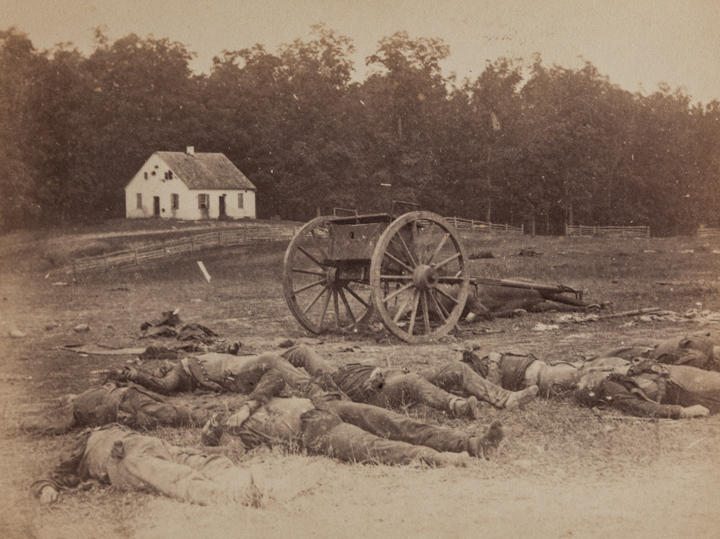 “Completely Silenced” —  Dead Confederate artillerymen as they lay around their battery following the Battle of Antietam. In the background is Dunker Church. 