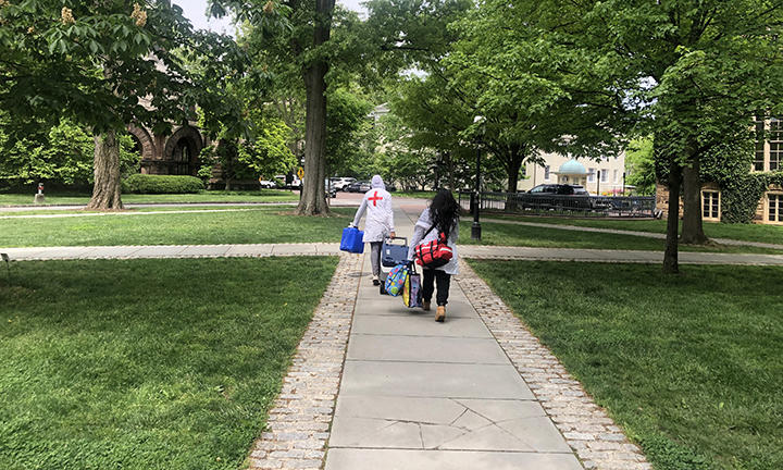 Two people carry bags down a pathway near Cannon Green.