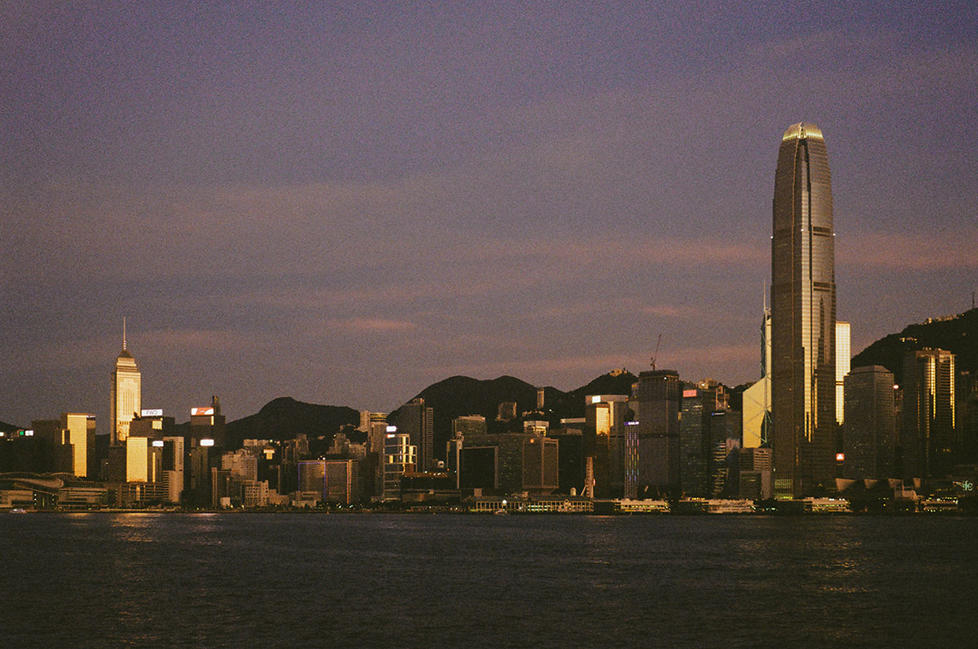 A Hong Kong city skyline photographed at dusk, the sky turning purple.