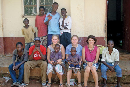 Annie Sprogell, wearing blue T-shirt, who is taking a gap year before entering Princeton, sits outside her house in Uganda with students and fellow teachers and gap-program participants.